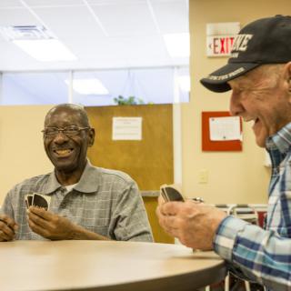 Two senior men enjoying a game of cards together, sharing laughter and camaraderie.