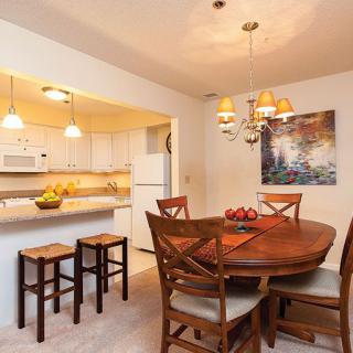 A cozy dining area adjacent to a modern kitchen with an oval wooden table and chairs under warm lighting.
