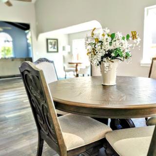 A cozy dining area featuring a wooden table adorned with a vase of fresh flowers, set in a bright and inviting home.
