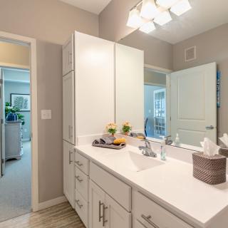 A modern bathroom featuring a sleek vanity with a large mirror and bright lighting.