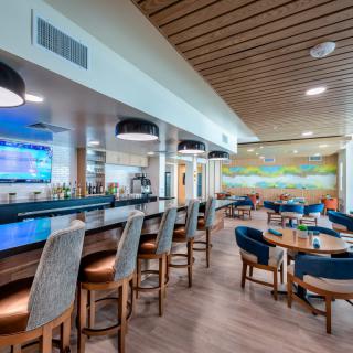 A modern indoor bar and restaurant with a seating area featuring a colorful mural.