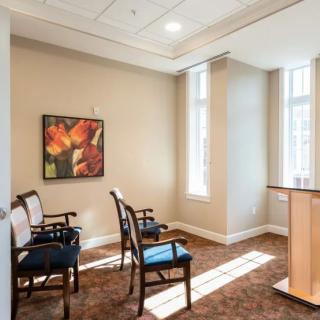 A small, well-lit room with chairs arranged around a podium and colorful artwork on the wall.