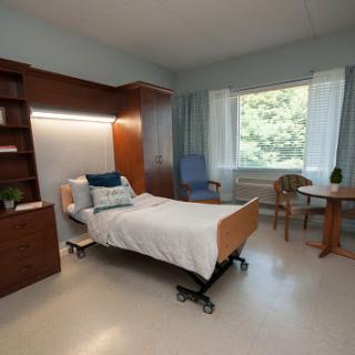 A well-lit hospital room featuring a patient bed, modern furniture, and a view of the outdoors.