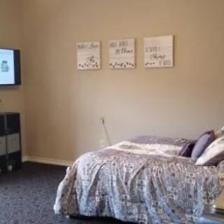 A cozy bedroom with a neatly made bed, wall art, and a TV.