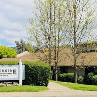A clinic building with a sign in front and trees surrounding the area.