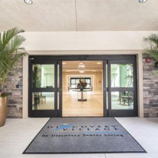 The entrance to a building with glass doors and a welcome mat on the floor.