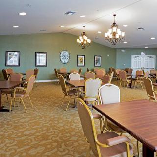 A spacious dining area with multiple tables and chairs, illuminated by chandeliers.