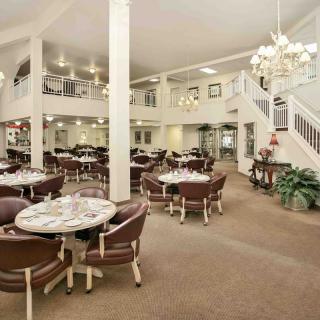 A spacious dining area with tables and chairs, bright lighting, and elegant chandeliers.