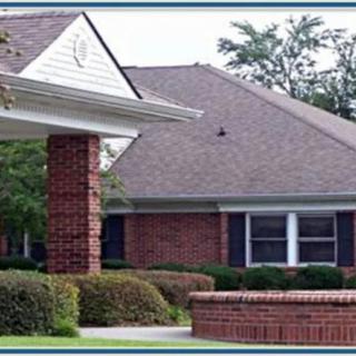 A brick residential house with a landscaped front yard.