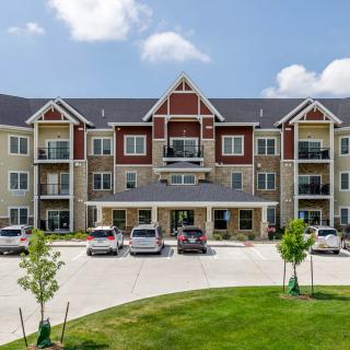 A modern apartment complex with a spacious parking area in a suburban setting.
