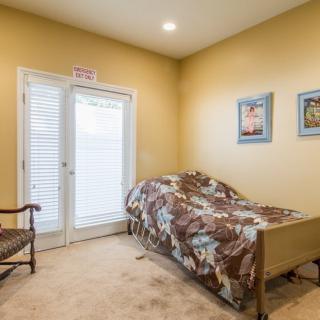 A cozy bedroom with a single bed, artwork on the walls, and a chair beside the window.