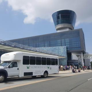 A shuttle bus parked in front of a modern airport terminal.