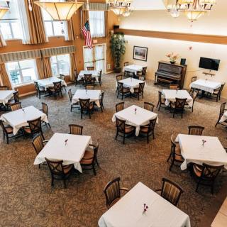A spacious and elegantly decorated dining room with multiple tables and chairs arranged neatly beneath chandeliers.