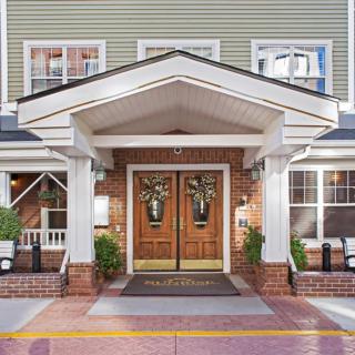 The inviting entrance of a charming building with wooden doors and white columns.