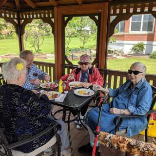 A group of seniors enjoying a meal together in a gazebo.