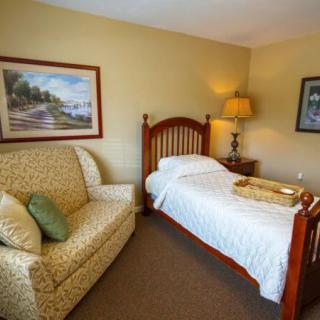 A cozy bedroom with a single bed, sofa, and warm lighting.