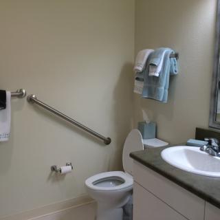 A clean and accessible bathroom with a toilet, sink, and grab bar.