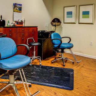 A cozy hair salon with blue chairs and wooden flooring.