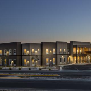 A modern commercial building illuminated at night with lights reflecting on the water.