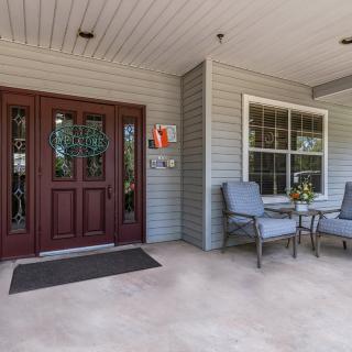 A cozy front porch with armchairs and a small table next to a wooden entrance door.
