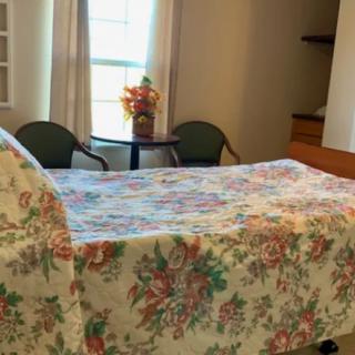 A cozy bedroom with a floral bedspread and a small table by the window.