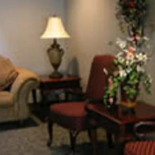 A cozy living room corner featuring a lamp, a sofa, chairs, and a table adorned with flowers.