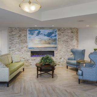 A cozy living room with modern furnishings, featuring a stone wall and fireplace.