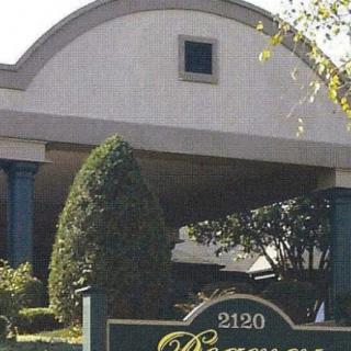 A hotel entrance with signage and landscaped greenery.