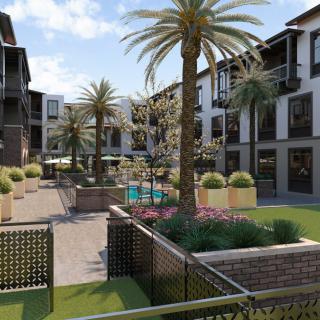 A modern apartment courtyard with landscaped gardens and palm trees.