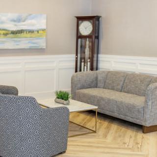 A cozy living room with a modern sofa set, a grand grandfather clock, and a contemporary coffee table.