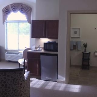 An interior room with a kitchenette, window, and visible bathroom area.
