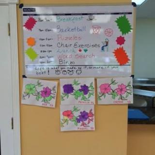 A decorated whiteboard displaying an event announcement with colorful decorations and floral artwork.