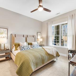 A stylish modern bedroom featuring a cozy bed with green bedding and ample natural light.