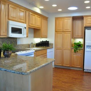 A modern kitchen featuring wooden cabinetry and a spacious granite countertop.