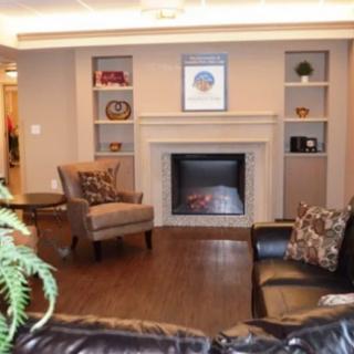 A cozy living room featuring a fireplace, armchair, and sofa with decorative shelves.