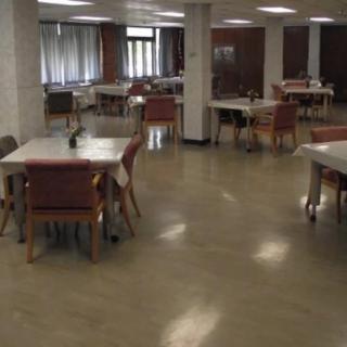 An empty dining area with multiple tables and chairs in a community setting.