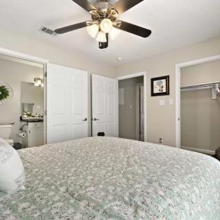 A cozy bedroom with a ceiling fan, bed, and open closet doors.