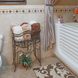 A well-organized bathroom with neatly arranged towels on a wire rack beside a bathtub.