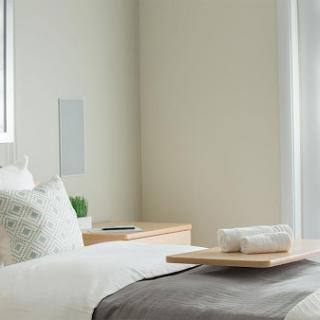 A serene and minimalist bedroom setup featuring neutral tones and modern decor.