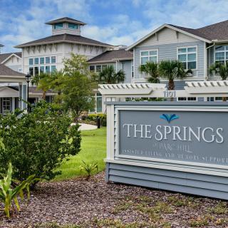 A view of The Springs residential building with a landscaped front and clear skies.