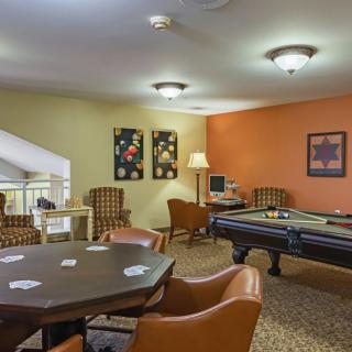 A cozy game room featuring a poker table and pool table, complete with comfortable chairs and decorative wall art.