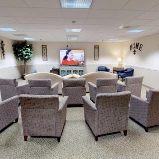 A comfortable lounge area with multiple chairs facing a television, ideal for meetings or relaxation.