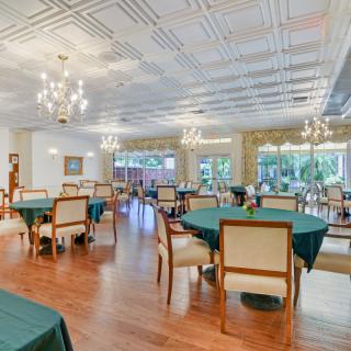 A spacious dining room with elegantly set tables and chandeliers.