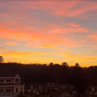 A vibrant sunset paints the sky in hues of orange and pink over a silhouetted landscape.