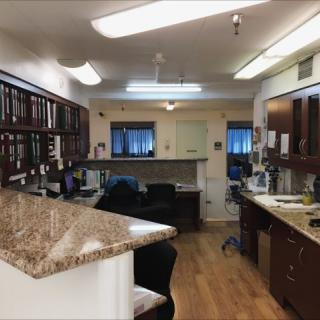 An office interior with desks, chairs, computers, and wooden flooring.