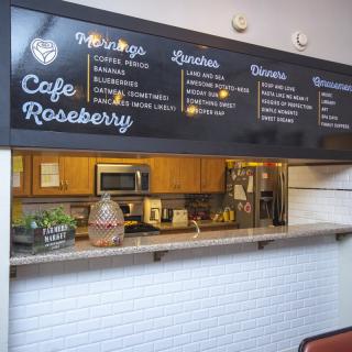 A cozy cafe counter with a menu displayed above, offering drinks, snacks, and desserts.