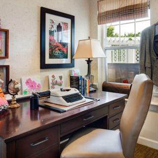 A cozy home office setup with a vintage typewriter, desk, and comfortable chair.