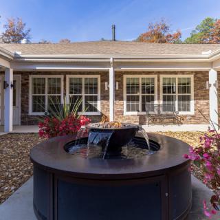 A serene courtyard featuring a central fountain surrounded by plants, with a backdrop of an elegant building facade.