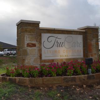 Entrance sign to a community or development, featuring landscaped flowers and brick architecture.