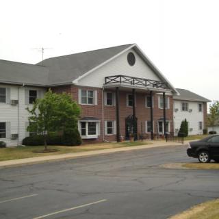 A view of a residential apartment building with a parking lot in front.